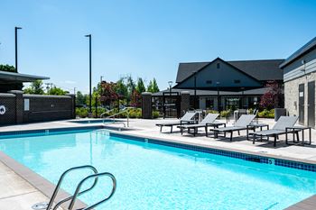 a swimming pool with chairs and a building in the background